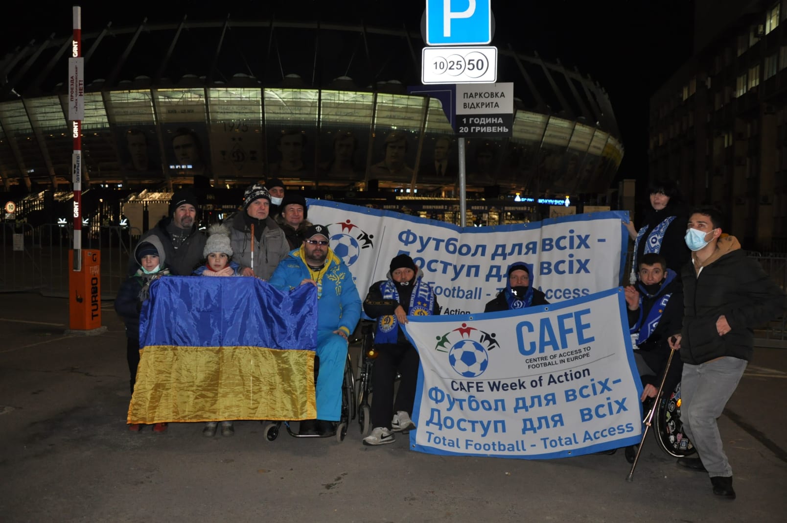 A group of disabled ukrainian fans outside the stadium in Kiev holding up a CAFE Week of Action banner alongside a Ukrainian flag.