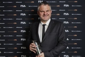Dave Messenger holding an award in front of an FSA-branded backdrop