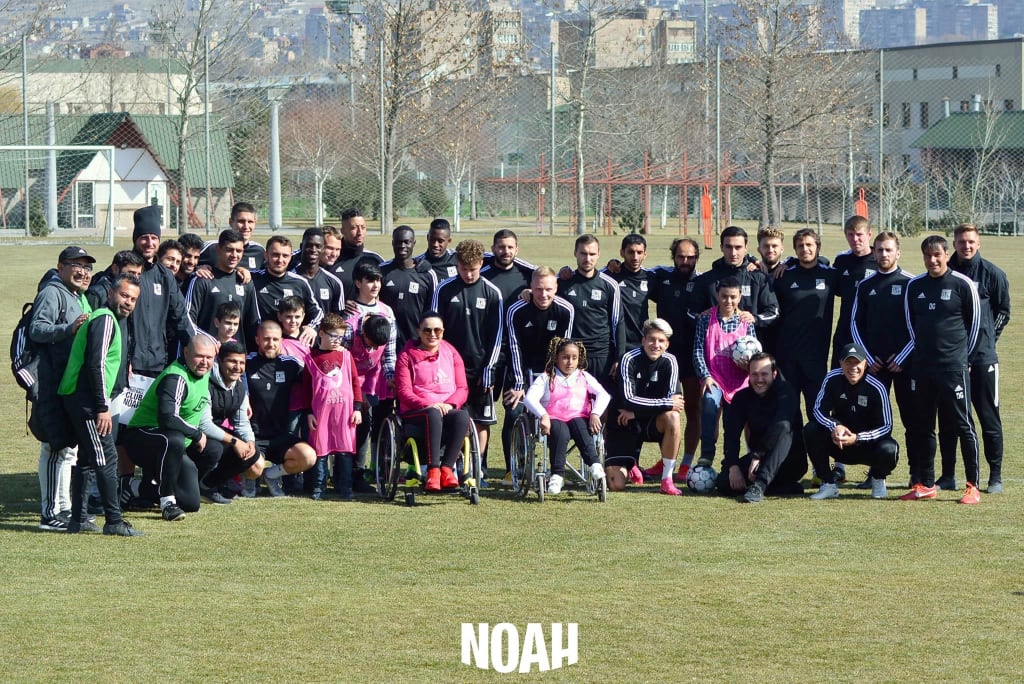 Gohar and the Noah football team posing for a group photo on a football pitch.